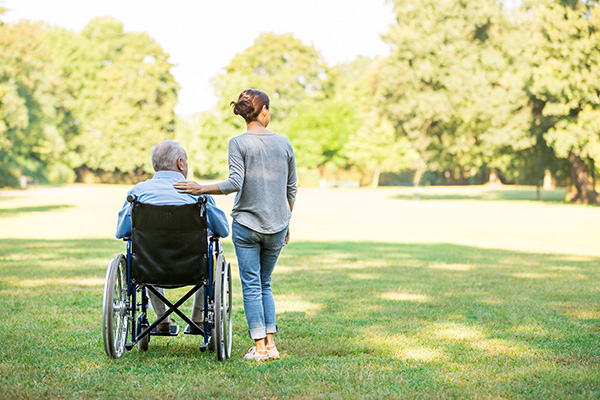 Image of a person in a wheelchair and one next to them in a park to represent arers direct